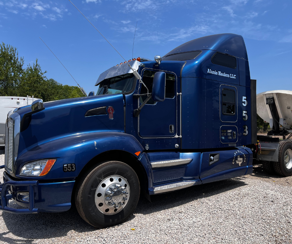 Blue Kenworth semi-truck with company logo, business branding, and USDOT identification graphics installed on the cab.