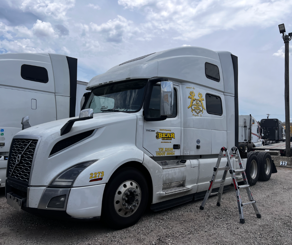 White semi-truck with company name, logo, USDOT number, and unit number graphics installed on the cab.