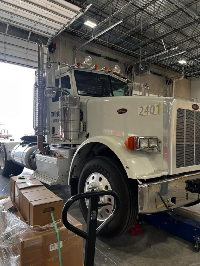 White Peterbilt semi-truck with company name, logo, and USDOT number decals installed on the cab.